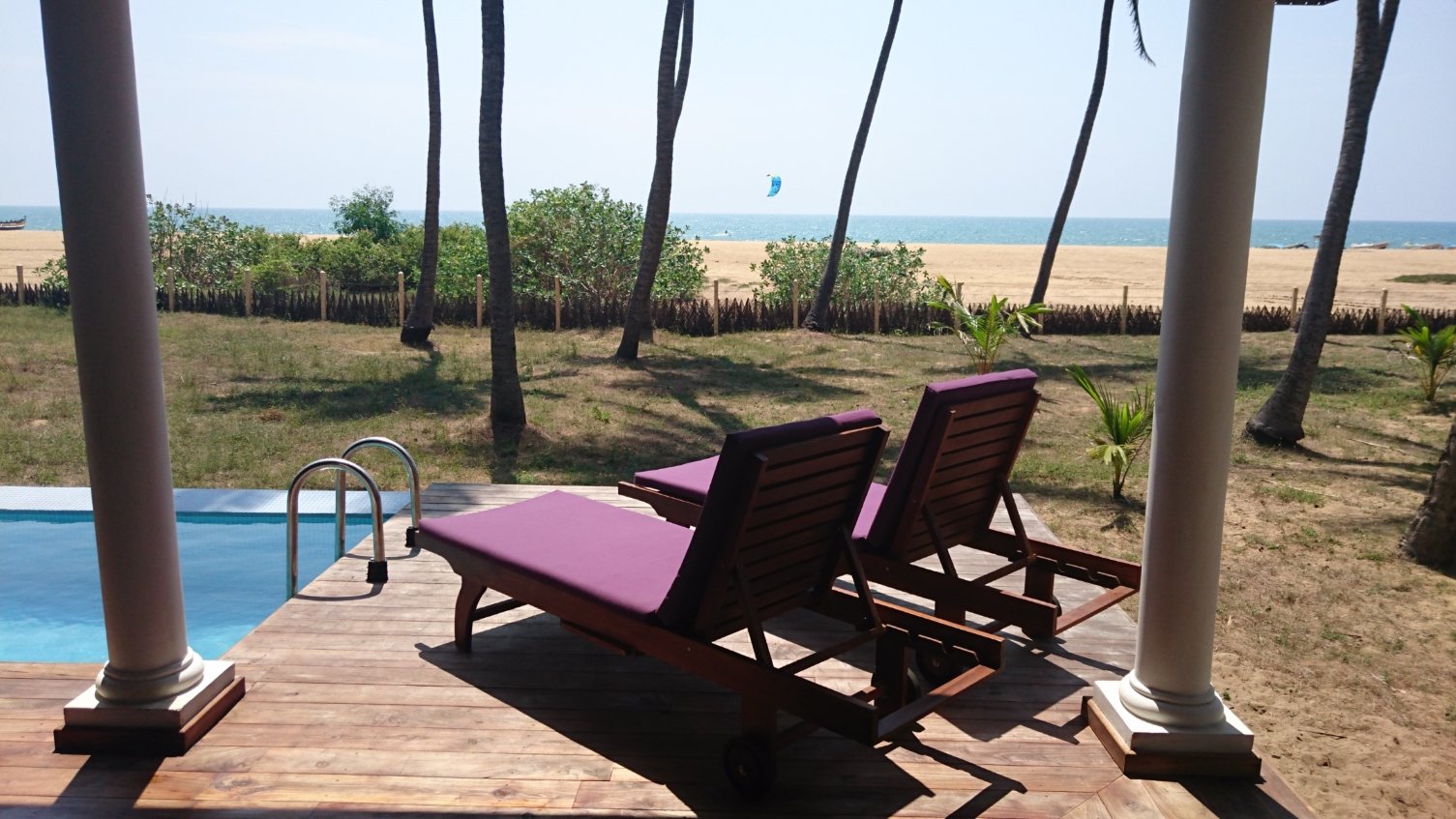 A kitesurfer on the ocean seen from the villa terrace, over the pool and beach